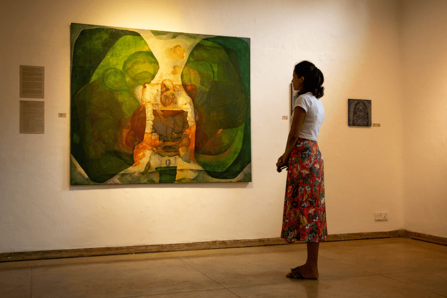 A visitor looking at a painting in a Colombo gallery