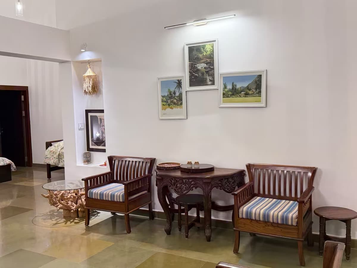Sitting area with wooden armchairs and landscape paintings